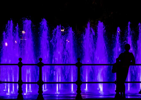 Mujer mirando una fuente colorida —  Fotos de Stock