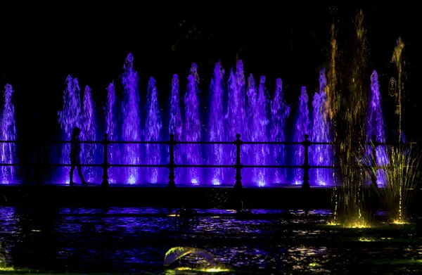 Kind blickt auf einen bunten Springbrunnen — Stockfoto