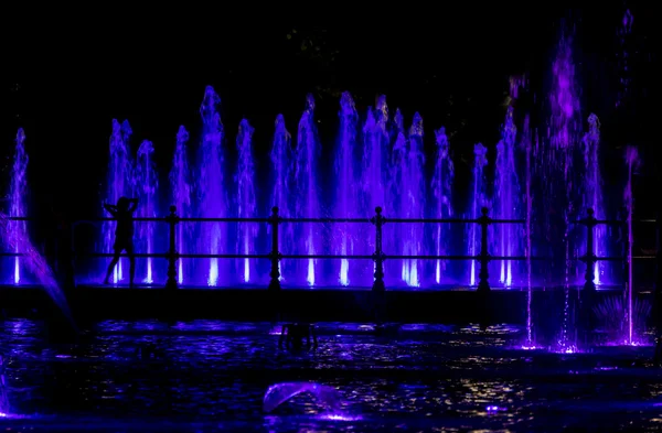 Enfant regardant une fontaine colorée — Photo