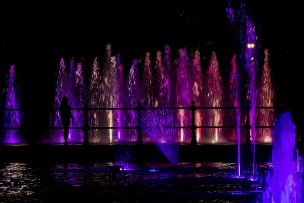 Enfant regardant une fontaine colorée — Photo