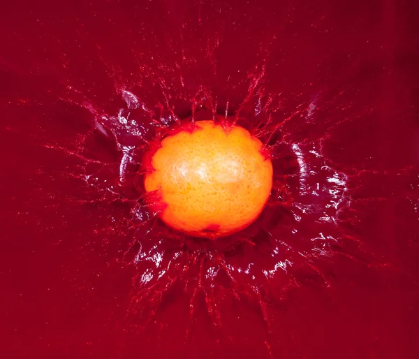 Mandarina en agua roja — Foto de Stock