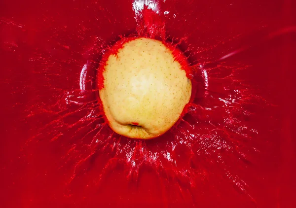 Żółte jabłko w czerwonej wodzie — Zdjęcie stockowe