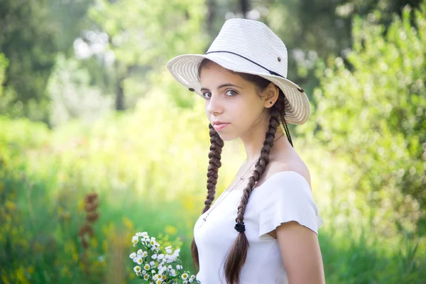 Mooi meisje met bloemen. Outdoor Portret daglicht. jongeren in een stro hoed buitenshuis Stockfoto