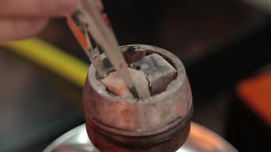 Arap kafesindeki shisha kasesindeki kömürler. Geleneksel nargile kömürü görüntüsü. Sigara içmek ve doğal ışıklandırmada boş vakit geçirmek için.