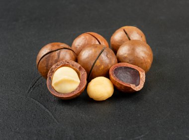 Koyu beton arka planda birkaç Macadamia fındığı.