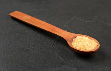 Koyu arkaplanda kahverengi şekerli ahşap kaşık