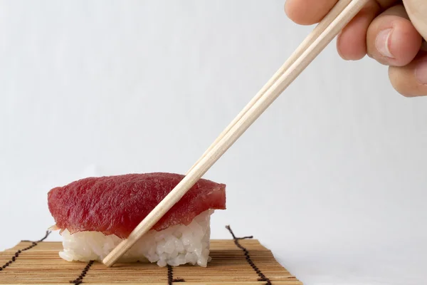 Ruce drží tuňák (Maguro) sushi pomocí hůlky na tatami Japa — Stock fotografie
