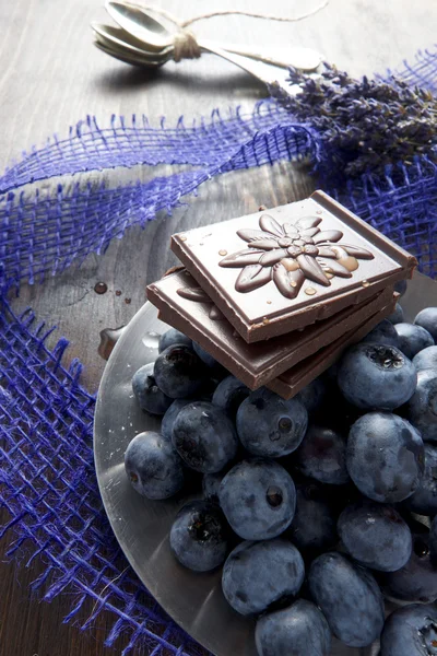 Arándanos y chocolate con lavanda y cuchara sobre tabla de madera —  Fotos de Stock