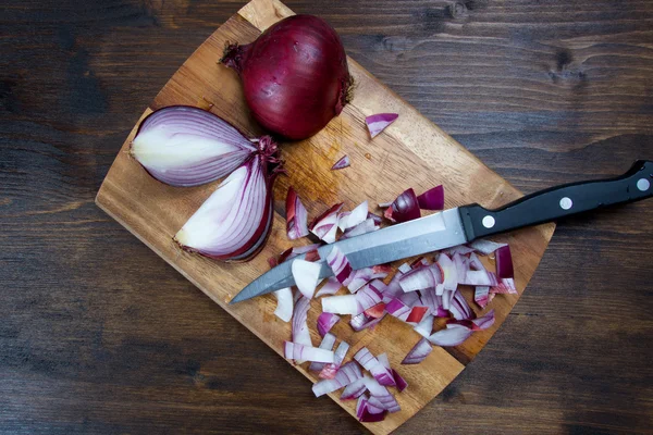 Red onion on wooden board with knife — Stock Photo, Image