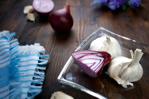 Red onion with garlic on brown wooden board and glass dish — Stock Photo, Image