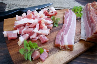 Taze çiğ domuz pastırması dilimlenmiş yeşil otla ahşap masada.