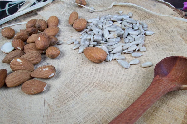 Almond and sunflower healthy seeds on wooden board with pattern — Stock Photo, Image