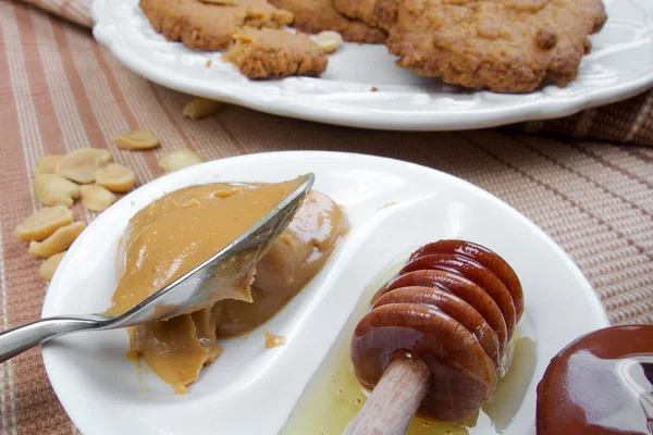 Sweet healthy peanut cookies on wooden table with honey — Stock Photo, Image