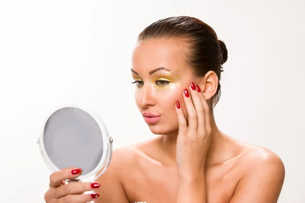 Altın makyaj. Kahverengi şık saç aynaya bakıyor güzel kadın