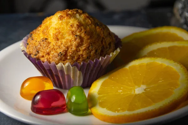 Sabroso postre de aspecto colorido con naranjas, magdalenas y dulces. Vista lateral de cerca. —  Fotos de Stock