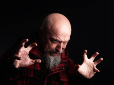 Huysuz, ihtiyatlı, orta yaşlı, gri sakallı, saçları kazınmış, kırmızı ceketli bir adam..