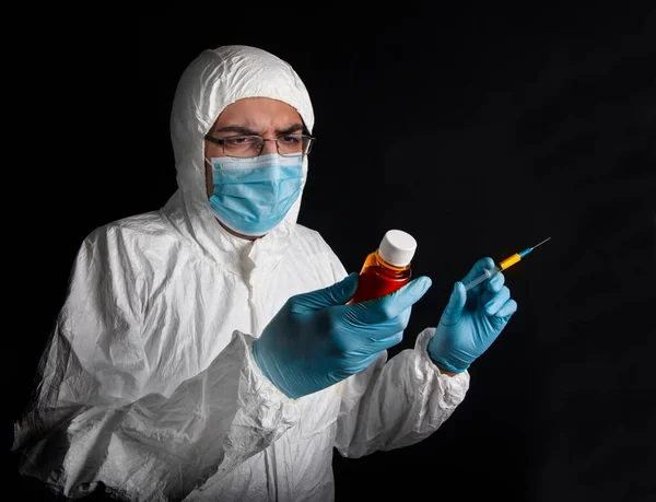 Young specialist in a protective suit, glasses, gloves and a mask at the time of medical manipulations