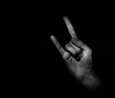 Keçi el hareketi işareti, koyu arkaplanda hafif aksanlı bir kol sembolü.