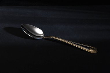 Siyah arka planda metalden yapılmış gümüş çay kaşığı.
