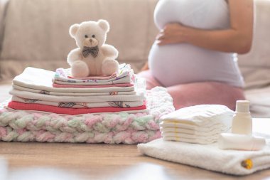 Hamile kadın doğumevi için hazırlanıyor, bebek eşyaları topluyor. Hamile bir kadın bebek kıyafetleri hazırlıyor ve planlıyor. Evdeki doğum hastanesi için hazırlık yapıyorum..