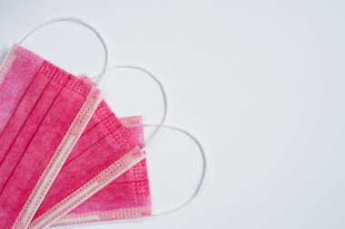 Beyaz arka planda üç pembe tıbbi maske. Yukarıdan bak. Düz yatıyordu