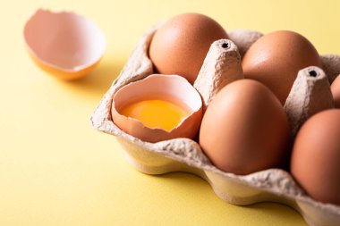 Sarı arka planda açık yumurta kutusundaki kahverengi tavuk yumurtaları. Doğal sağlıklı beslenme ve organik tarım kavramı. Yakın çekim görünümü