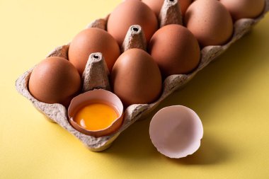 Sarı arka planda açık yumurta kutusundaki kahverengi tavuk yumurtaları. Doğal sağlıklı beslenme ve organik tarım kavramı. Yakın çekim görünümü