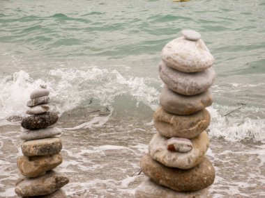 Zen ve doğa uyumu kavramı deniz kıyısında sabah meditasyonunda taş yığını deniz sahilinde armoni taşları ve çakıl taşlarını plajda tekboynuz taşlarıyla gevşetiyor.