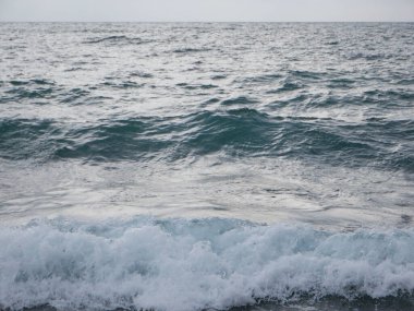 Deniz dalgaları, dalgalar ve köpüklerle kayalık deniz kıyısında kırılıyor. Karadeniz kıyısında dalgalar.