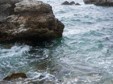 Dalgalar ve köpüklerle kayalık deniz kıyısı. Denizin kayalık kıyılarında dalgalar kayalıklarda dalgalar dalgalar ve köpüklerle deniz dalgaları..