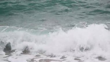 Güçlü bir okyanus dalgası dramatik bir yakın çekim ile sahile çarpar. Temiz turkuaz su, beyaz deniz köpüğü ve dinamik sıçramalar enerjik ve ferahlatıcı bir kıyı manzarası yaratır. Doğa, seyahat, rahatlama, çevre veya deniz manzaraları.