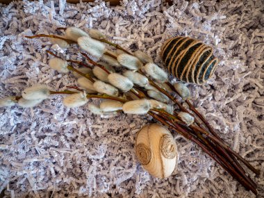Elegant spring composition with blooming pussy willow branches and rustic handmade Easter egg decoration wrapped in twine. Soft pastel colors natural materials  seasonal atmosphere Ideal concept for Easter greeting, spring holiday.