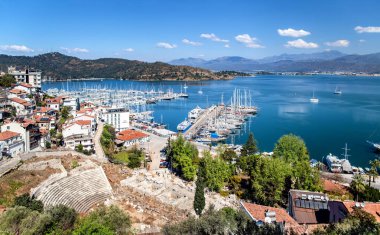 Fethiye, Türkiye - 28 Mart 2021: Yat, tekne ve dağlarla Fethiye limanının manzarası. Ön planda Antik Tiyatro 'nun kalıntıları var. Mugla Eyaleti.