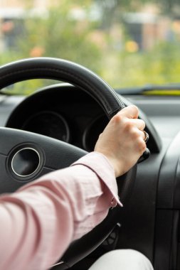 Yakın plan pembe gömlekli bir araba direksiyonunda bir insan, araç içi.