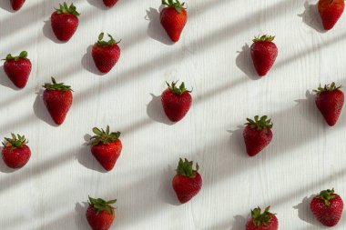 Beyaz arka planlı lezzetli taze çilek, güneş ve gölge, stüdyoda dekor, sağlıklı yaşam tarzı.