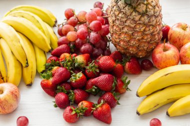Beyaz arka planda lezzetli taze meyvelerin yakın plan çekimi, ananas, muz, elma, çilek, üzüm ve muz, sağlıklı yaşam tarzı, stüdyo
