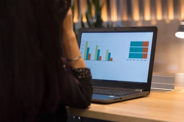 detail of a woman working on her computer in an office illuminated with warm light, business woman in her office with a computer reviewing analysis and statistics