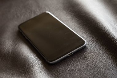 Yumuşak ışık ve kontrast ile çok zarif bir deri koltukta metalik kenarlı modern cep telefonu