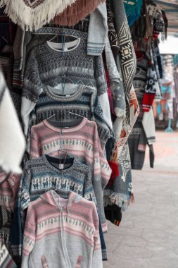 Modern tasarımları olan çeşitli örgü ve renkli kazaklar bir zanaat pazarında, giysi ayrıntıları