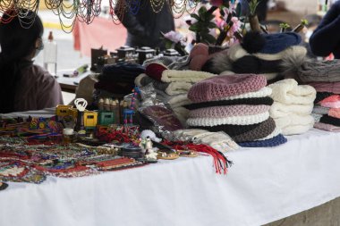 çeşitli el sanatları ve dışarıdaki bir mağazada bir masaya istiflenmiş renkli yün giysiler, nesnelerin dokusunun ayrıntıları.