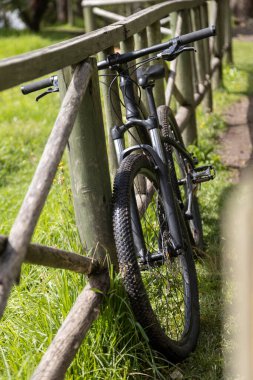 Parktaki ahşap korkuluklara dayanan bisiklet, spor ve macera günü