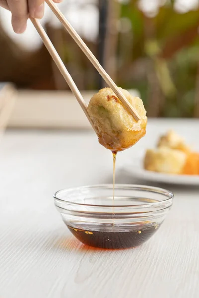 用手拿着一个用木棍调好的寿司卷蘸酱汁 详细研究亚洲食物的质感 — 图库照片