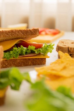 Tam buğday ekmeği, peynir, marul ve bir tabak nacho ile hazırlanmış sandviçler, evde hazırlanmış lezzetli yemekler, atıştırmalıklar.