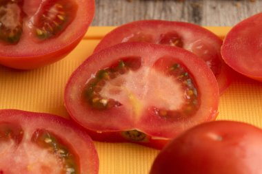 Taze domates dilimlerine yakın, tohumları doğrama tahtasının üzerinde, sebze dokusu stüdyoda sağlıklı bir besin maddesi.