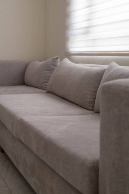 Minimalist mobilyalar ve konforu ve tarzı vurgulayan zarif ev dekoruyla çevrili, parlak, rahat bir oturma odasında, yumuşak beyaz kumaştan iki koltuklu kanepe..