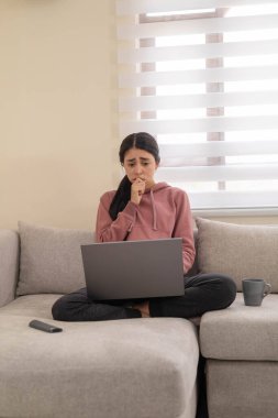 Bir kadın dizüstü bilgisayarında rahatsız edici bir şey okurken endişe gösterir. Çevrimiçi stres, dijital aşırı yükleme ya da duygusal tepki konuları için ideal.