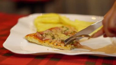 Lüks bir restoranda yemek yiyen sofistike bir kadın çatal bıçak kullanarak pizza ve patates kızartması yiyor. Zarif atmosfer, zarif stil ve modern yemek deneyimi..