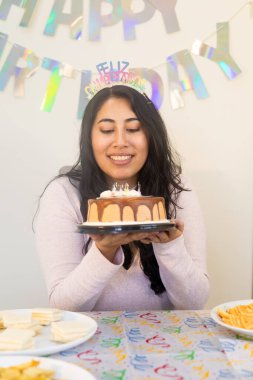 Mutlu kadın doğum günü kutlaması sırasında süslenmiş masada oturuyor, gülümsüyor ve bayram anının tadını çıkarıyor..