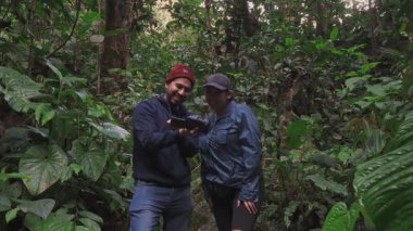 İki yürüyüşçü, birlikte görüntüleri incelerken eğlenceli bir anı paylaşmak için sık bir orman yolunda mola verir..