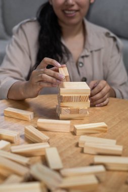 Çöktükten sonra ahşap bir istif kulesini yeniden inşa eden bir kadının yakın plan çekimi, hazırlık, odaklanma, sabır ve kapalı masa üstü oyununu yeniden başlatma.